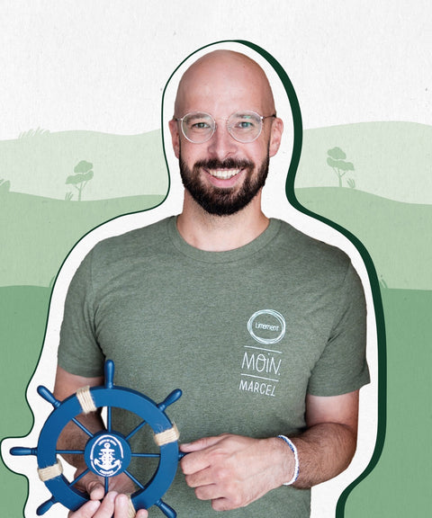 Limoment Teammitglied Marcel G. hat eine Glatze, einen dunkelbraunen Bart, eine Brille, grüne Augen und trägt ein grünes T-Shirt und lächelt.