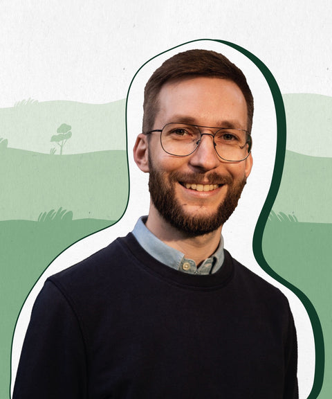 Limoment Teammitglied Moritz hat kurze braune Haare und Bart, eine Brille, braune Augen, trägt ein blaues Shirt und lächelt.