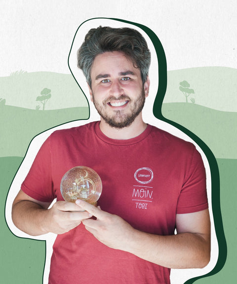 Limoment Teammitglied Tobi hat kurze braun-graue Haare und Bart, braune Augen, trägt ein rotes T-Shirt und lächelt.