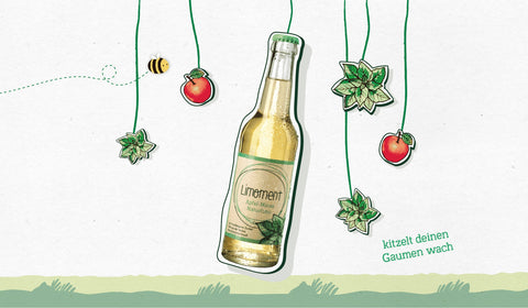 Eine Glasflasche Limoment Apfel-Minze Naturlimo hängt an einem Seil, daneben eine fliegende Biene und der Satz kitzelt deinen Gaumen wach.