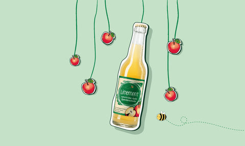 Eine Glasflasche Limoment naturtrübe Apfel-Spendenschorle hängt an einem Seil, daneben Äpfel und eine fliegende Biene vor einem grünen Hintergrund.